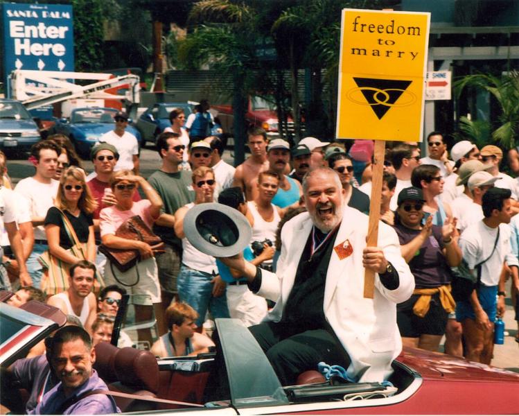Reverend Troy Perry carrying a "freedom to marry" sign from the back of a car in a Los Angeles Christopher Street West pride parade. Undated.